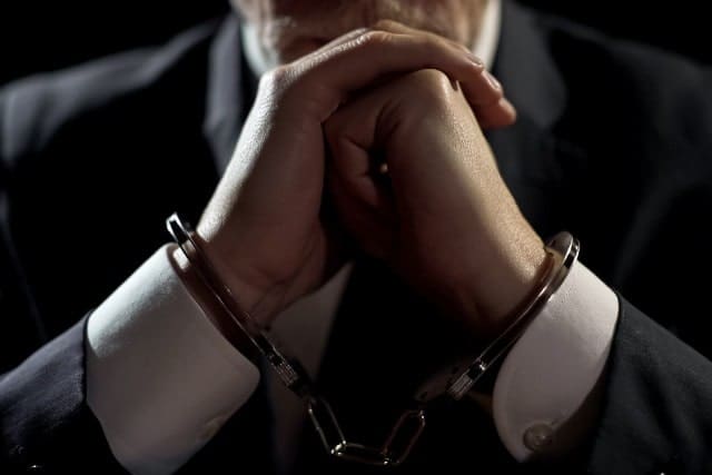 Man in suit wearing handcuffs