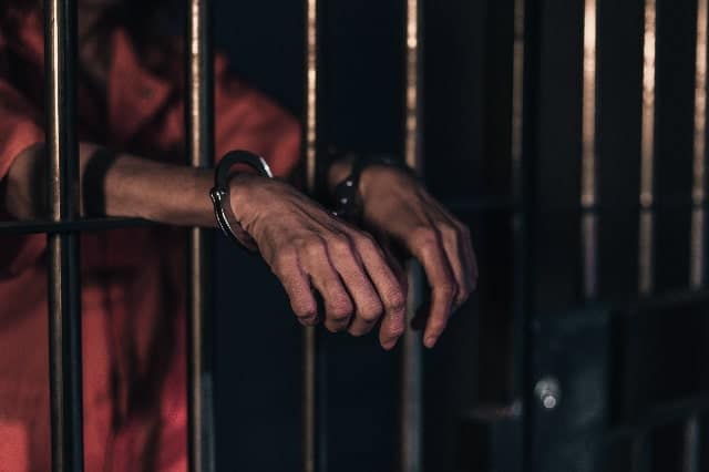 Man behind bars with handcuffs